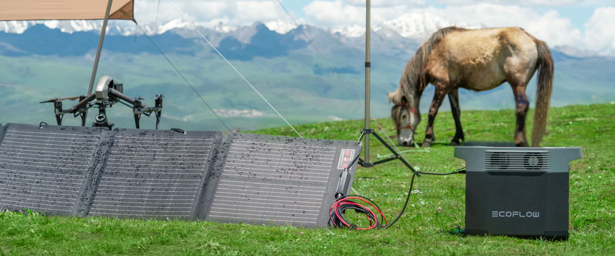 A portable power station coupled with solar panels on a field next to a drone and a horse